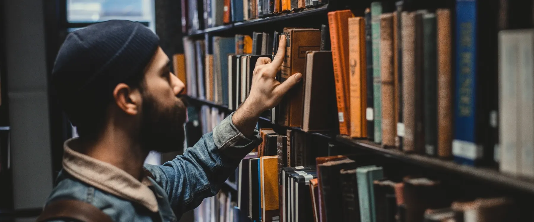 A researcher selecting a book from library shelves